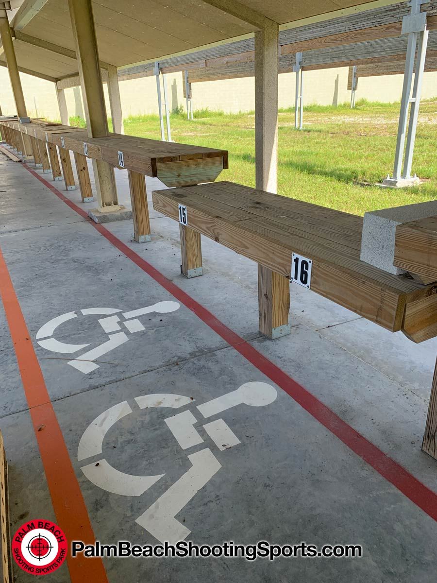 Wheelchair-accessible shooting positions marked on the concrete floor of a covered firing line